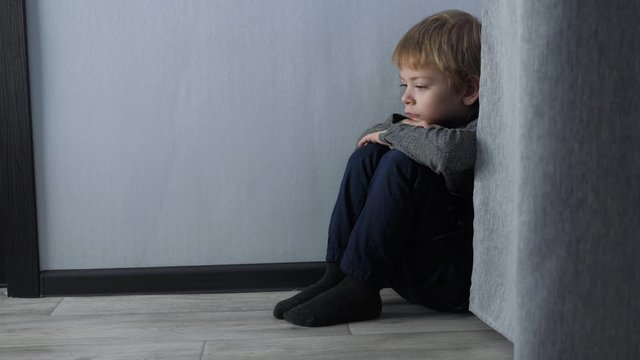 sad upset boy sitting in the corner. Child punished lifestyle sitting crying in the corner. Domestic violence concept. Child abuse
