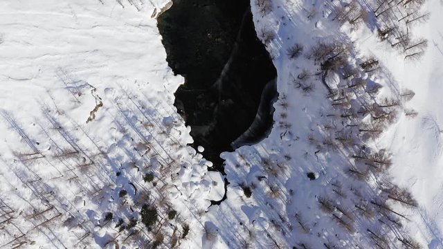 top view aerial over snowy blue alpine lake in sunny winter day .Europe Alps mountains outdoor establisher.4k drone overhead flight establishing shot