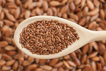 Brown flax seed background. Linseed grain wooden spoon texture. Flaxseed oil preparation.