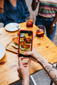 Close up of a tattooed hand taking a photo with a smartphone of