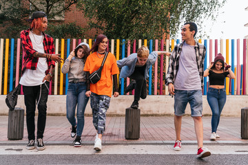 Group of urban friends gang walking in city skate park.