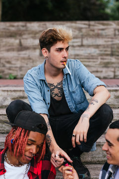 attractive young man with a cigarette in his mouth hanging out with some friends