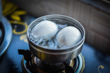 Fototapeta na wymiar egg boiling in silver bowl 