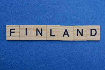 gray word finland from small wooden letters on a blue table