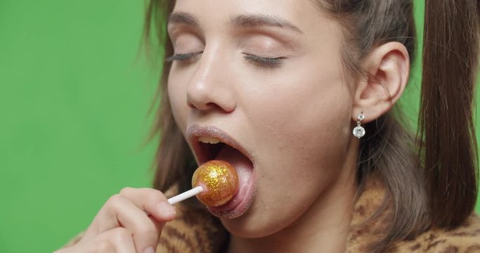 female model wearing leopard fur coat licking candy