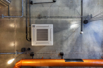 looking up on gray concrete ceiling with halogen spots and edison lamps in loft office room with...