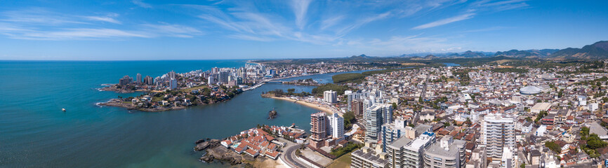 Fototapeta na wymiar Beautiful drone view of Guarapari city center with beaches, houses and buildings on the waterfront streets and transparent sea on a sunny summer day with blue sky. Espirito Santo state, Brazil.