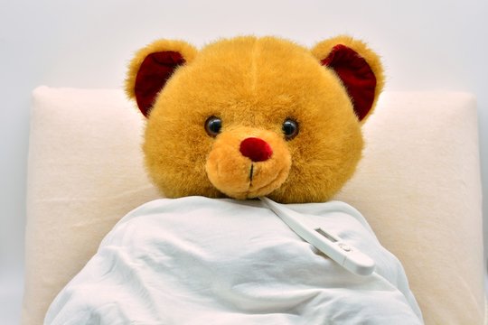 Oso de peluche enfermo en la cama con el term&oacute;metro puesto