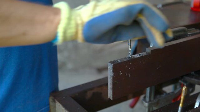 A man with protective gloves on his hands cuts a thread in metal for future connection