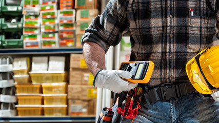 Electrician holds multimeter tester in hand, helmet with protective goggles. Construction industry, electrical system. 