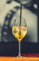 Prickelnder Cocktail im Glas mit Strohhalm, Limetten und Eis auf Tisch in Bar