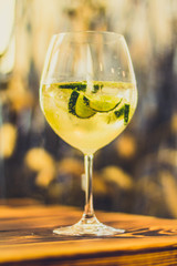 Prickelnder Cocktail im Glas mit Limetten und Eis auf Tisch in Bar