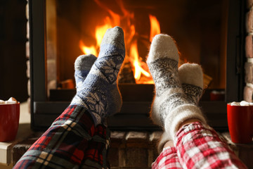 Couple in pajamas resting near fireplace indoors, closeup. Winter vacation