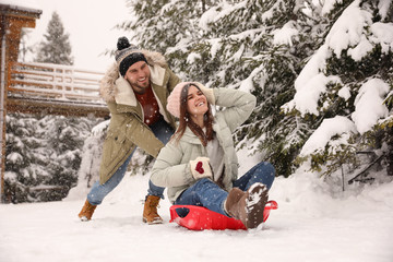 Couple having fun and sledding on snow. Winter vacation