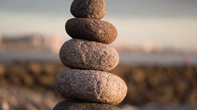Balanced stone pyramide on shore of the ocean at dawn. Sea pebbles tower closeup symbolizing stability, zen, harmony, balance.