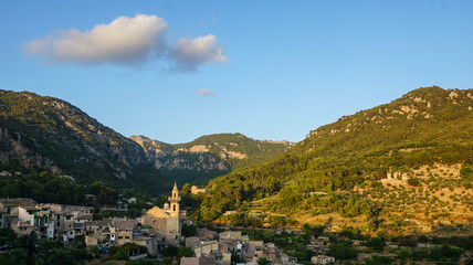 Fototapeta na wymiar Picturesque Spanish village of Valldemossa in a valley surrounded by green mountains on the sunset 