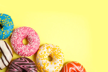 Delicious glazed donuts on yellow background, flat lay. Space for text