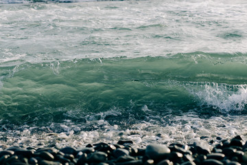 a sea wave arrives on the shore with black volcanic sand . beautiful natural background in Iceland