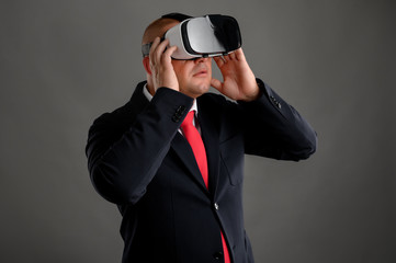 Businessman dressed in black suit wearing virtual reality VR glasses