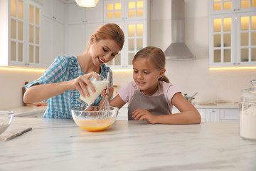 Mother and daughter making dough together in kitchen