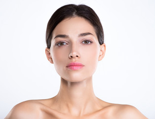 Fototapeta premium Portrait of beautiful young brunette woman with clean face. Beautiful face of young adult woman with clean fresh skin - isolated on white. Front portrait of woman with beauty face. .Beauty concept