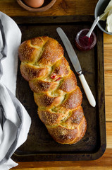 Traditional sweet Easter bread with raisins, dried cherries on an old baking tray jam and butter. Cozonac - Bulgarian Easter bread. Rustic style. Vertical, top view, close up.