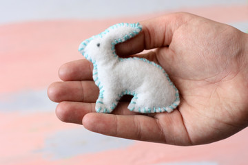 Easter handmade white felt toy bunny in the palm of your hand