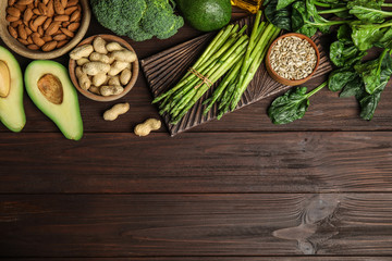 Different products rich in vitamin E on wooden table, flat lay. Space for text