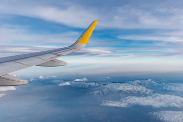 Naklejka na ściany i meble ala de avión airbus a320 sobre sierra nevada, españa. se ve el cielo azul con nubes y las montañas