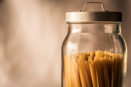 Spaghetti inside a transparent cristal jar with a gray metal cap