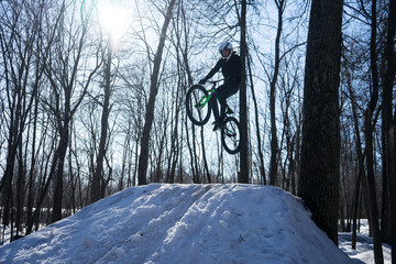 Mountainbike rider cycling in winter dirt jumping. An athlete in a helmet does a trick on a bicycle...