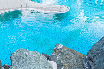 Top view of a blue water pool surrounded by stones. The concept of summer, relaxation, spa, aqua park, sports, architecture