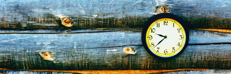 Old clock hanging on wall of logs. Panorama.