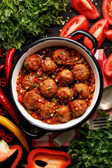 Meatballs in tomato sauce with the addition of aromatic herbs in an enamel dish top view