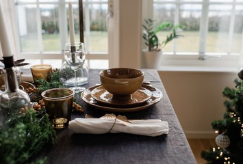gold plates and cutlery on a decorated dinner table at home