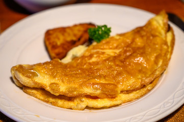 Homemade omelette made from three scrambled eggs served with fresh parsley and potato hash brown