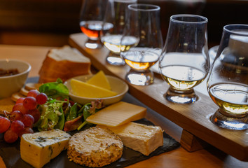 Fototapeta na wymiar Tasting of original scottish cheese and whisky, plate with scottish cheeses and variety of Scotch in glasses