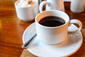 White cup with black coffee and  hot milk jug