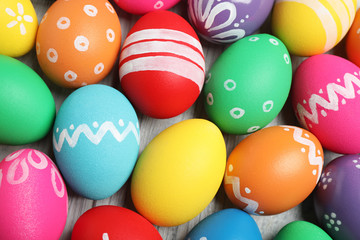 Many bright Easter eggs on wooden background, above view