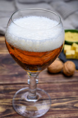 Glass of Belgian abbey blond beer  and stone plate with cheeses made by monks from cow milk with  fenugreek and mustard seeds