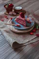 Red Velvet cake on a blue plate with strawberries and pure cocoa with a rustic background with flowers and cloth napkins