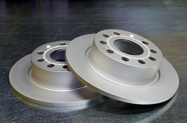 New brake discs of a modern car close-up on a steel background.  Sale and storage of spare parts....