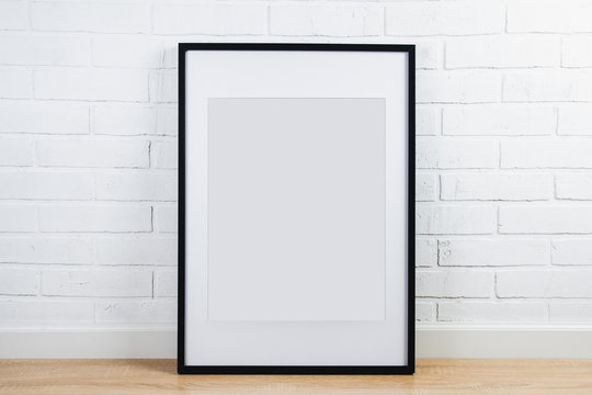 Black frame for painting or poster on white brick wall