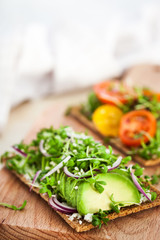 Avocado rye toasts with green herbs, onion and cherry tomatoes, healthy food