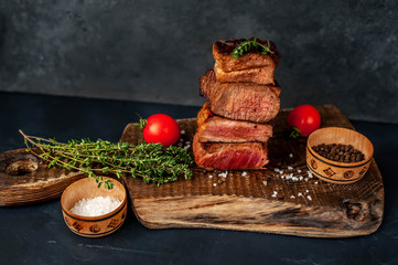 four grilled steaks with spices on a stone background. Four types of meat frying Rare, Medium,...