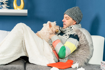 man with flu cuddles with his dog on the couch