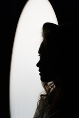 Silhouette portrait of young female model wearing hat in noir style.