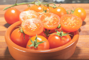 tomates cherry en rama recien recogidos en mader y vasija de barro