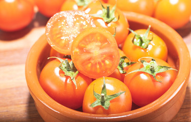 tomates cherry en rama recien recogidos en mader y vasija de barro