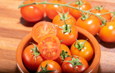 tomates cherry en rama recien recogidos en mader y vasija de barro